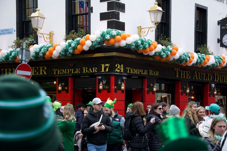 Festive crowd outside Temple Bar in Dublin during St. Patrick's Day with green decorations.