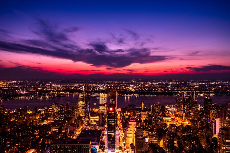 Stunning aerial view of New York City skyline against a dramatic sunset sky with vibrant lights.