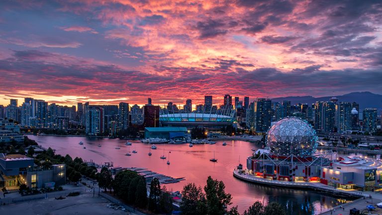 Stunning view of Vancouver cityscape with colorful sunset sky reflecting on harbor water.
