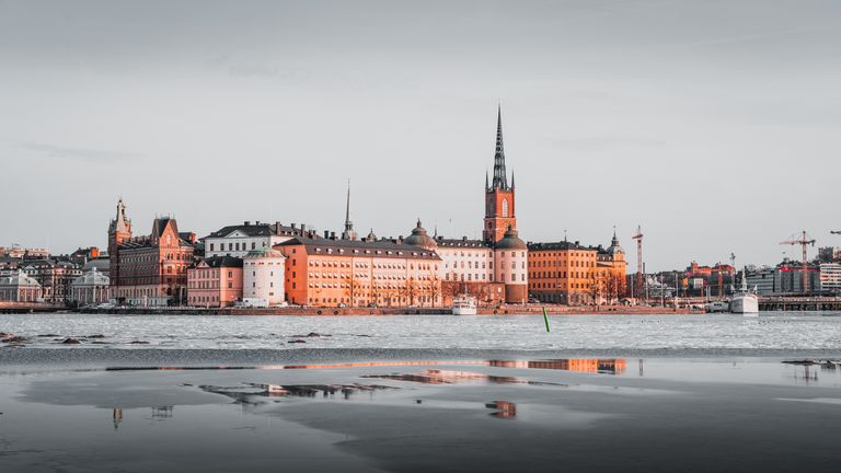 Beautiful view of Stockholm's skyline reflecting on icy waters at dusk.