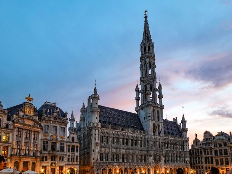 Gothic style Brussels Town Hall illuminated during sunset in the historic Grand Place.